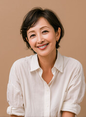 Fototapeta premium Smiling middle aged Japanese woman in white shirt on beige background