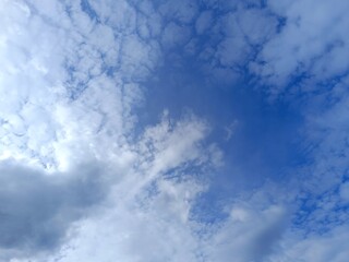 Obraz premium Mixed cloud formations in a blue sky. Textured white altocumulus and darker grey clouds. Natural daytime weather background with copy space