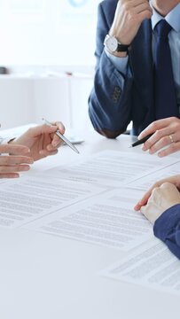 Business colleagues reviewing contract documents during an office meeting, discussing terms, and preparing for agreement signing, focusing on legal consultation and partnership discussion