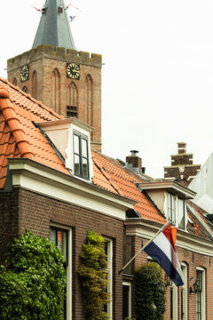 Dutch house with flag and historic church tower in Naarden