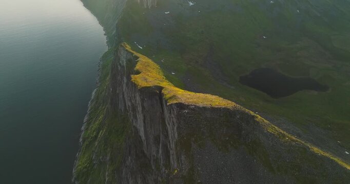 Ridge view at Segla mountain summit from the Hesten hike on Senja Island, Norway. Sheer granite cliffs rise dramatically from the water in a breathtaking Arctic landscape.