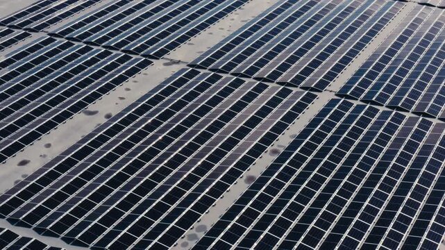A high-angle view captures long rows of rooftop solar panels, emphasizing clean energy, industrial scale, and the precise geometry of modern renewable infrastructure.