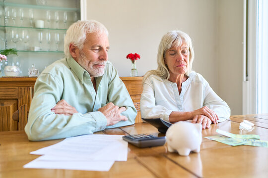 Retirement Planning Challenges: Senior Couple Facing Financial Insecurity, Reviewing Documents With Calculator And Piggy Bank