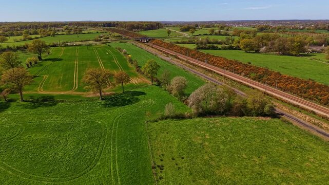 ocage farmland with hedgerow field system and railway corridor in Mayenne department Pays de la Loire region France with pasture and arable plots, drone forward glide aerial shot
