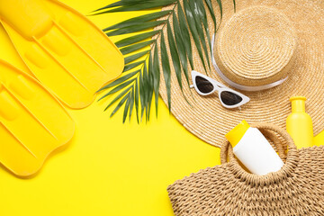 Beautiful composition with beach accessories, flippers and sunscreen on yellow background © Pixel-Shot
