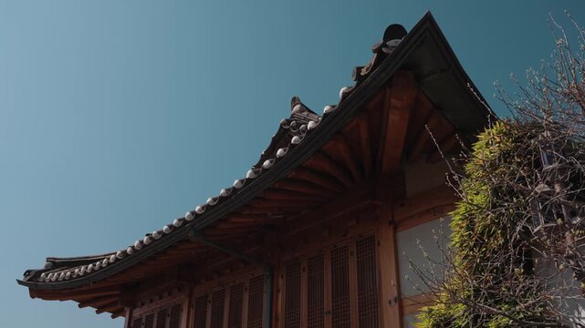 Traditional Korean hanok house architecture in Bukchon Hanok Village, Seoul, South Korea, featuring wooden details, curved tiled roof, and historic residential design under clear blue sky.