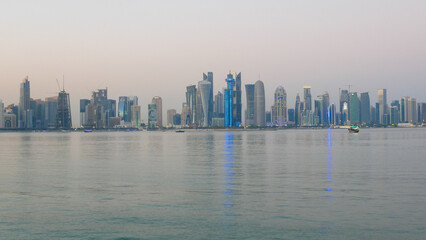 Fototapeta premium Modern Doha skyline reflecting on calm waters of the Arabian Gulf, Qatar, showcasing contemporary skyscrapers and tranquil waterfront cityscape.