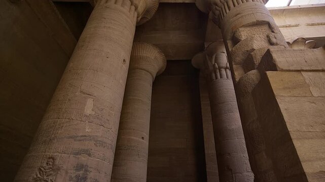 Ancient Egyptian Philae Temple. with massive carved stone columns covered in hieroglyphs, low angle view highlighting detailed reliefs and architectural grandeur.