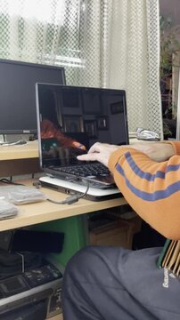 Aut&oacute;nomo tecleando y trabajando en el ordenador port&aacute;til escribiendo un correo electr&oacute;nico teletrabajando desde casa con laptop y pantalla laburando como freelance