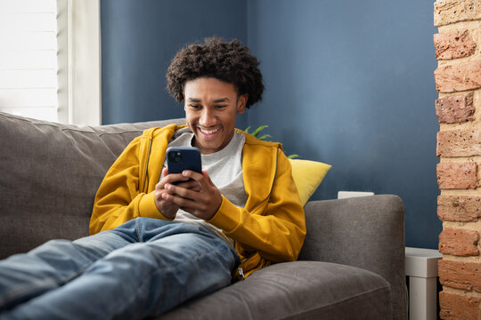 Teen boy Relaxing on Sofa Using Smartphone at Home