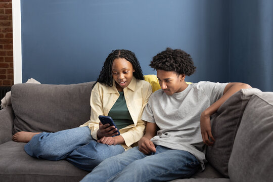 Teens Focused on Phone Together on the Couch