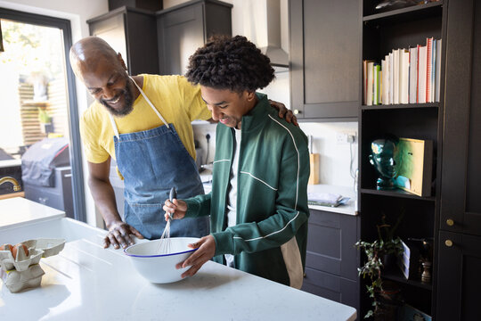 Father and teenage son cooking together in cozy kitchen space