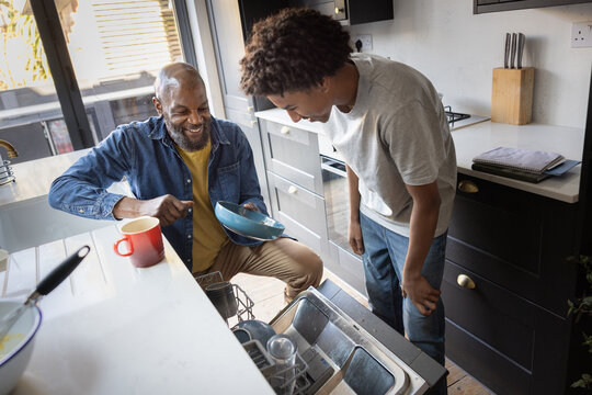 Father and son doing chores in modern kitchen