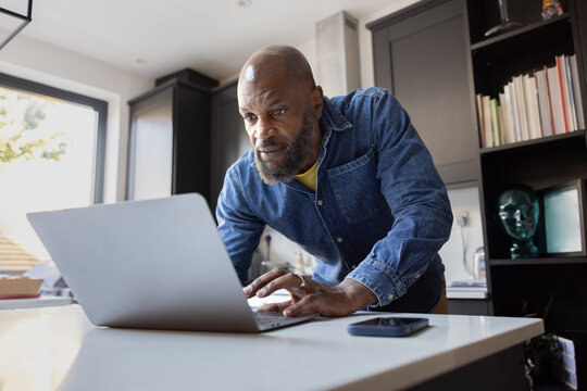 Focused Man Working on Laptop in his kitchen