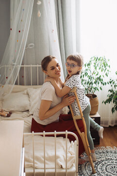 Mother embracing happy child with disability at home