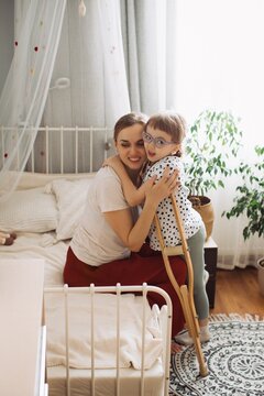 Mother embracing child with physical disability at home