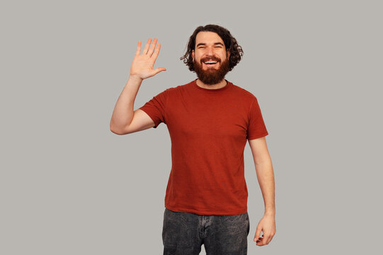 Caucasian Man Waving Hand, Warm Greeting Expression, Studio Portrait With Red Shirt And Beard, Welcoming Host