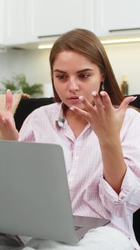 Young woman at home joins video meeting argues with coworkers and gestures then ends call. Caucasian girl on sofa raises palm points to screen finishes talk after hard conflict shows anger and stress