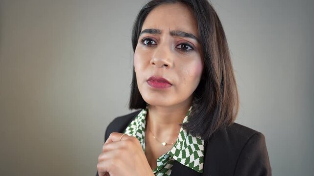 Close-up portrait of thoughtful confused young Asian businesswoman manager thinking considering future plans, isolated over grey studio background.