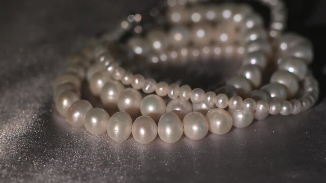 Pearl necklace strands on soft gray background, bridal elegance concept.
Delicate pearl strands arranged in soft composition on a neutral gray background. 