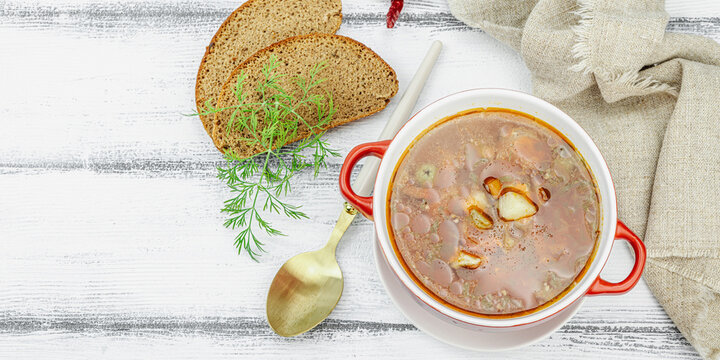 Meat solyanka soup with sausages, olives and vegetables served on table. Traditional bowl