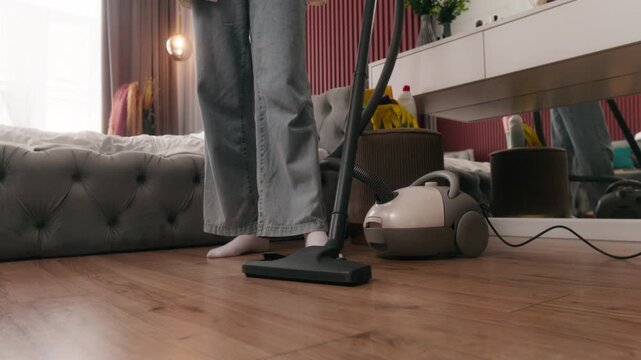 Close up of vacuum cleaner female legs cleaning floor in bedroom unrecognizable woman girl doing household chores with modern hoover indoors housewife maintaining tidy apartment cleanup tenant flat