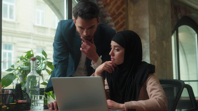 Hindu business team businesswoman in hijab with laptop incorrect data computer online failure Indian leader businessman coming in office helping solve problem typing pc cooperation corporate learning