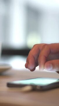 Close-up of a person's hand using a phone in a cafe