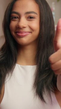 Portrait smiling American woman showing hey you thumb up like gesture in luxury pink bathroom Hispanic cheerful ethnic female girl looking at camera smile recommend beauty routine skin care procedure