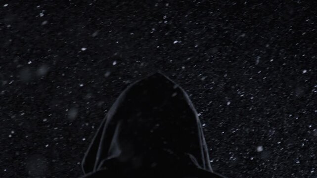 Snow falls around hidden man. Snow particles fill dark scene. Cinematic snow concept shows mystery. Winter snow footage feels dramatic.