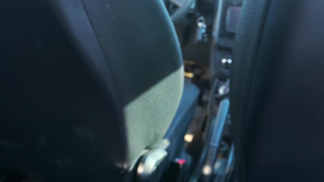 Rear view inside car showing manual driver seat sliding forward, backward using adjustment mechanism. Seat moves smoothly to change driving position, improve ergonomics, comfort, control in vehicle