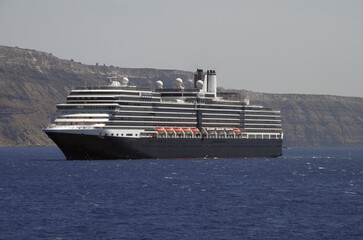 Luxury cruiseship cruise ship liner Eurodam anchoring at sea on sunny summer day during Mediterranean Greek Island Santorini caldera cruising with shore and rocky island in background © Tamme Wichmann