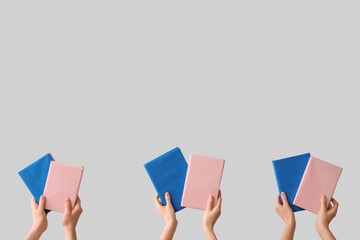 Hands holding books on grey background