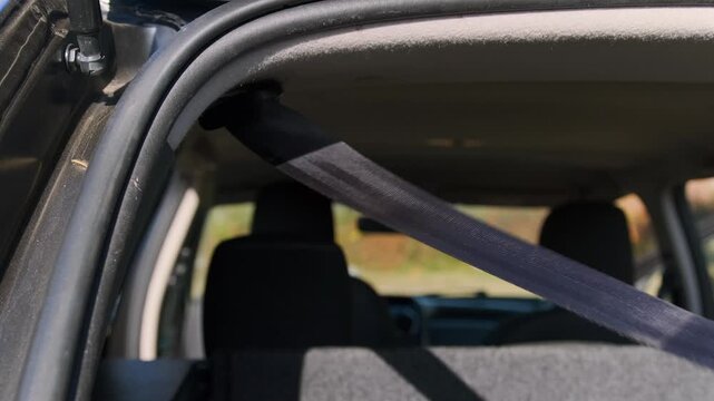 Close-up inside car trunk pulling out cargo securing strap, fixing luggage in SUV storage area, safety transport solution for goods stabilization in vehicle trunk space