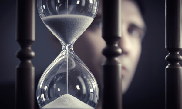 Hourglass measuring time during Jerome Powell speech focusing on economic pressure and decision making