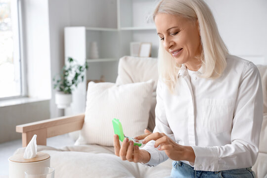 Mature woman selecting pills from pillbox at home