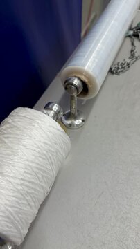 Transparent film white rope on counter showcasing closeup of dispenser with clear stretch film and dense white twine spool ready