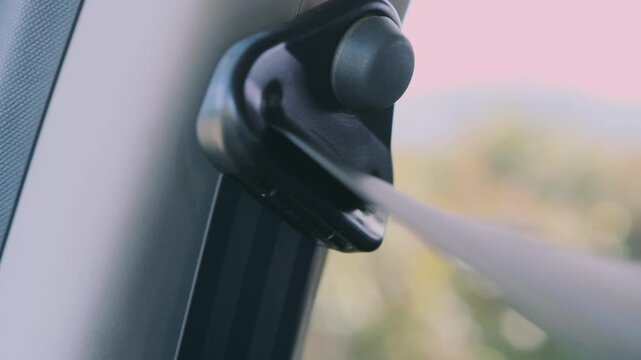 Inside car pulling seat belt showing safety system operation. Belt extends smoothly from pillar, preparing for fastening, highlighting protection, compliance, driving safety, secure travel in vehicle