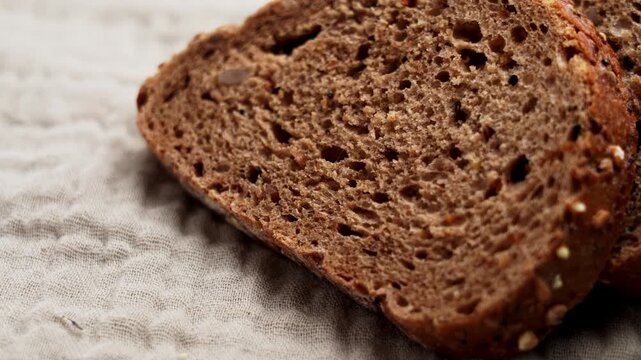 Slices of rustic German rye bread on a natural linen fabric. Artisanal baking and healthy breakfast traditions concept