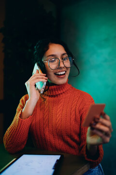 Happy young woman using credit card and smartphone for secure online transaction. Mixed race professional making payment or order via mobile app, smiling and enjoying digital lifestyle in studio.