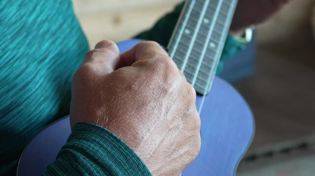 Ukulele playing music, close up of hands strumming purple instrument