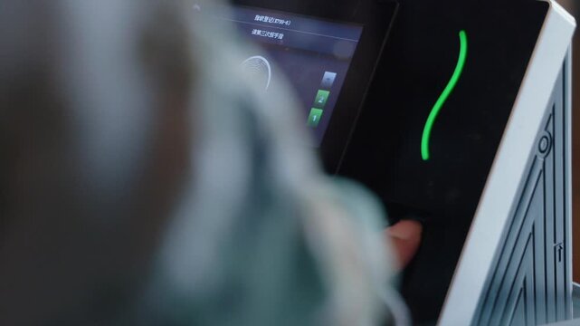 Worker using a biometric scanner to record attendance and clock in for security and identification