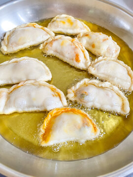 Traditional Malaysian karipap curry puff frying in hot oil during homemade cooking preparation.
