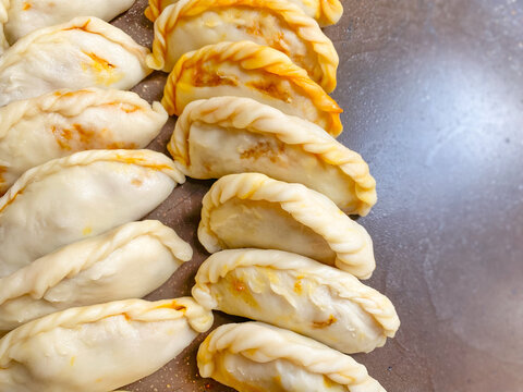 Close up of handmade uncooked karipap curry puff showing detailed pastry folds before frying.