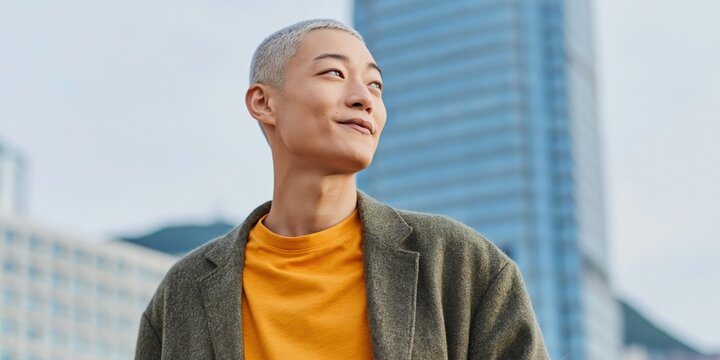 Young person smiling while looking upward in cityscape