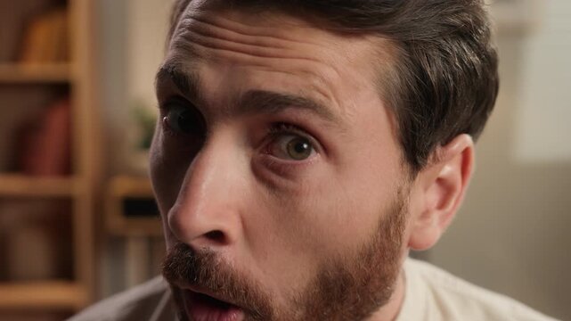 Closeup amazed Caucasian middle-aged man looking at camera staring gazing with one eye at home shocked wonder stunned adult male look with interest shock surprise amazement astonishment emotion indoor