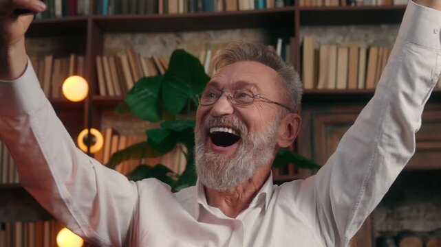Caucasian old retired business man waiting result yelling winning with mobile phone at office emotional senior aged elderly businessman male wait prize betting casino yell win with smartphone happy