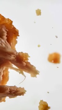 Vertical video: Tugging fried chicken pulling apart in studio, revealing meat fibers and crust