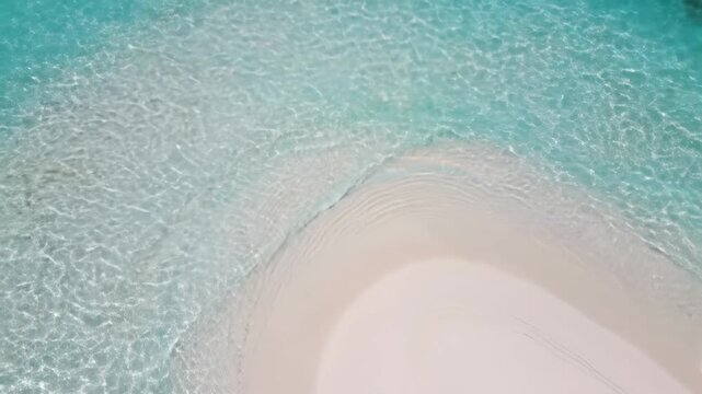 Clear turquoise ocean water gently laps against a sandy beach, showcasing the serene transition from water to shore in a tropical coastal environment