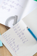Fototapeta premium Open copybook with math formulas and pen on wooden table, closeup